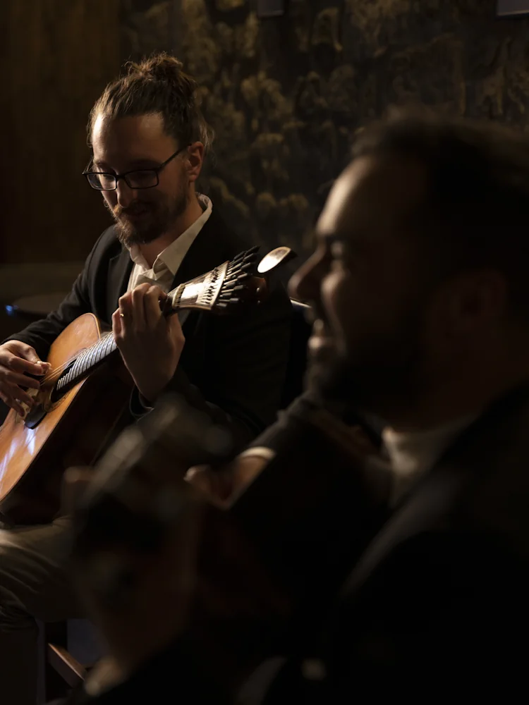 Guitarrista absorto a tocar guitarra portuguesa durante um concerto de Fado ao vivo no Porto, no Fado Maior do Porto